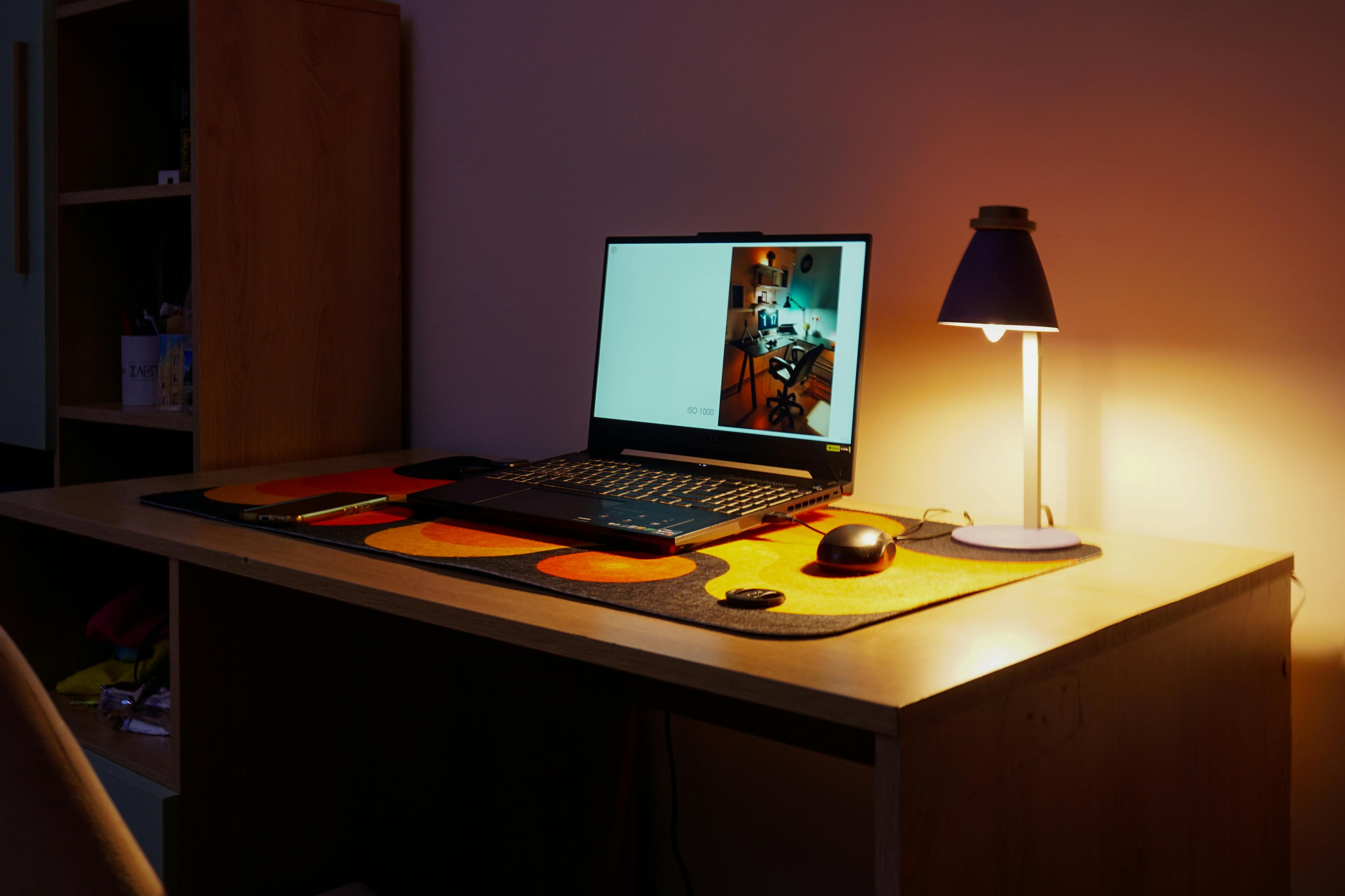 A minimalist desk setup with warm task lighting and a laptop.