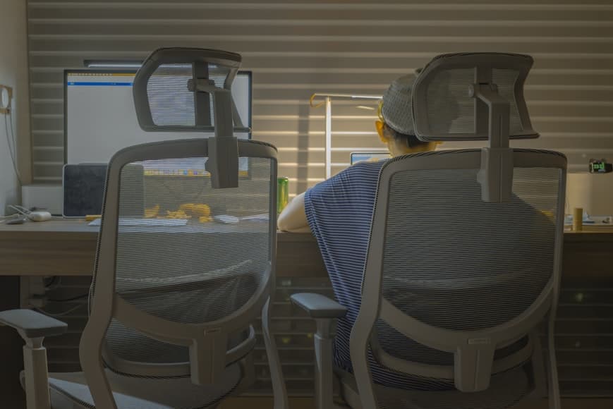 Two mesh ergonomic office chairs with headrests at a desk workstation.