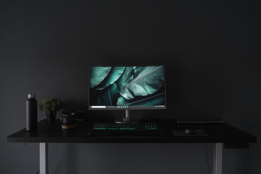 A compact desk setup in a bright home office with a monitor, laptop, and neatly arranged workspace items.