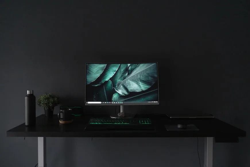 A compact desk setup in a bright home office with a monitor, laptop, and neatly arranged workspace items.