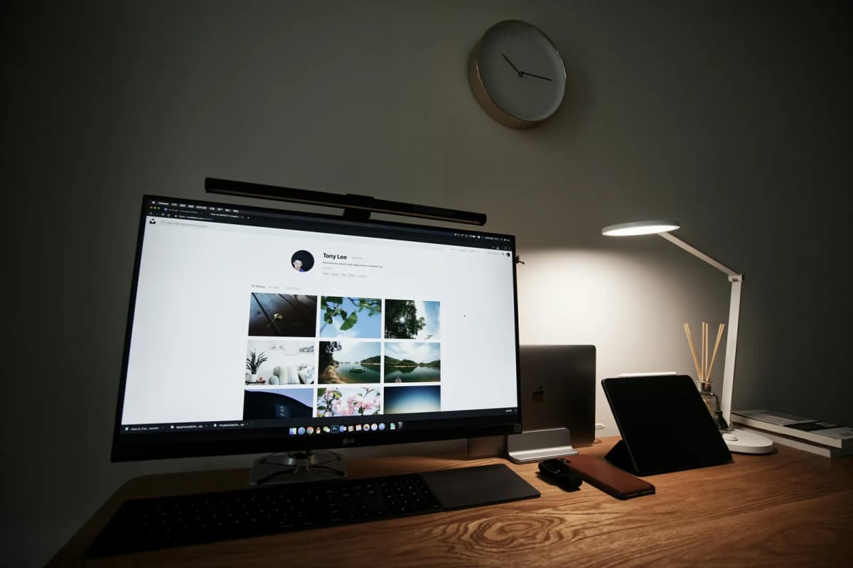 A desk lamp casting a small pool of light on a dark desk while the rest of the room stays in shadow