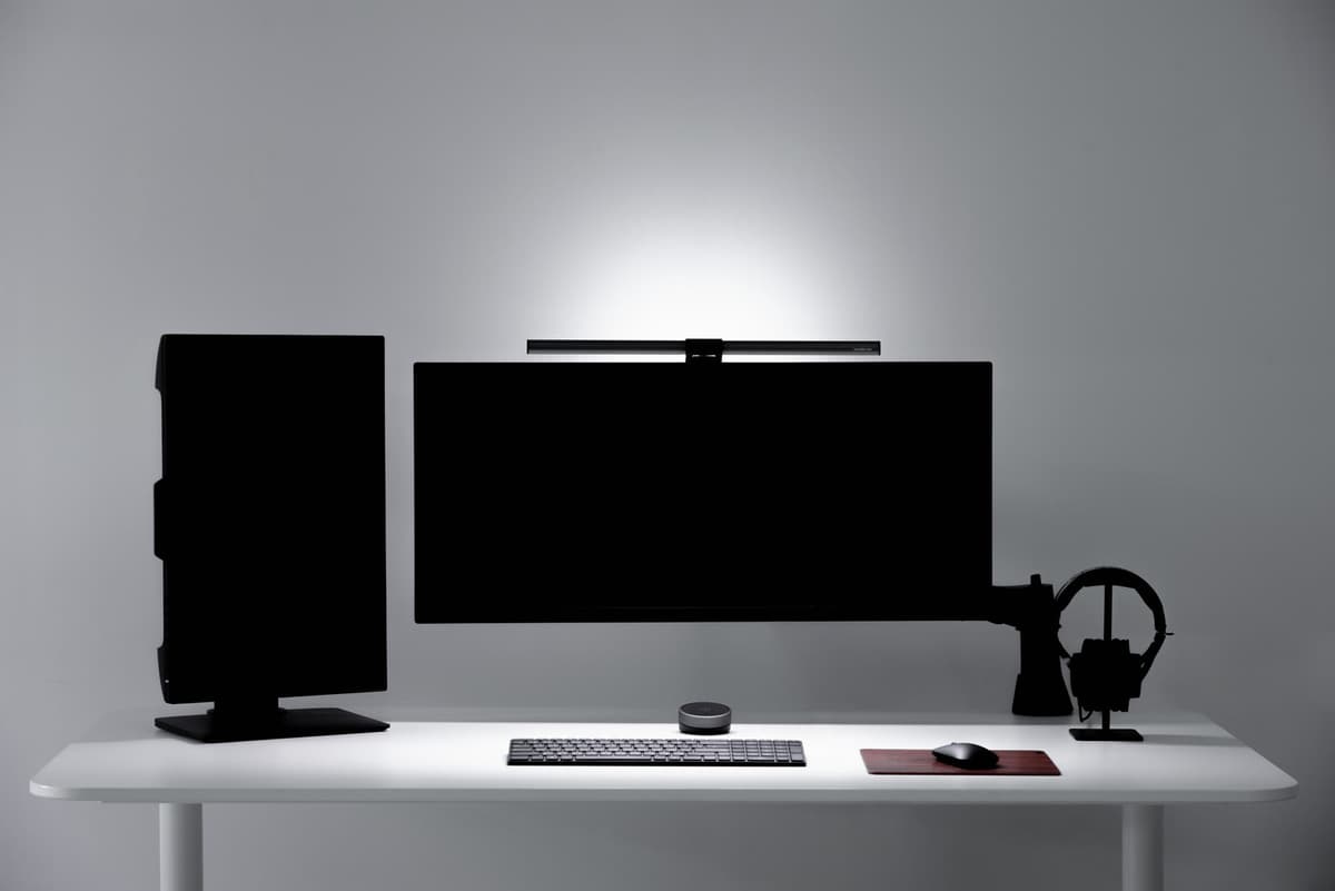 A warm home office desk lit by a monitor light bar in an official BenQ image.