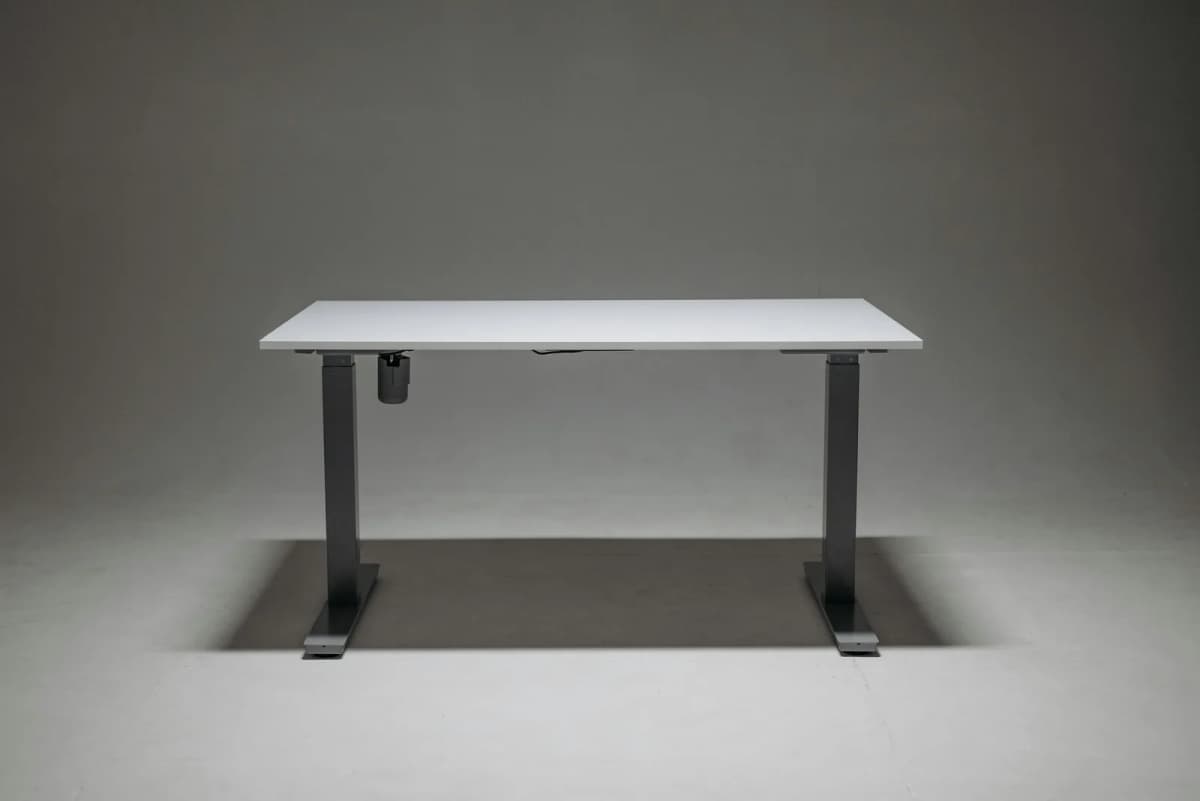 A minimalist white standing desk against a neutral gray backdrop.