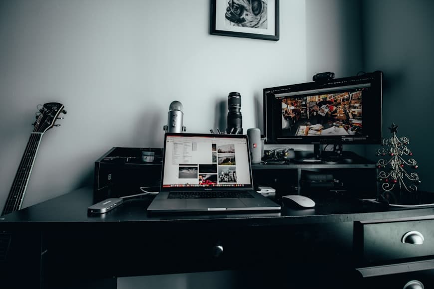 A small home office desk with a laptop, notebook, and warm light in a lived-in room.