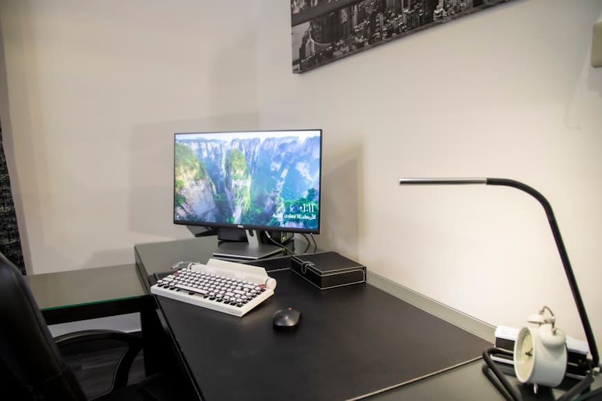 A compact home office corner with a desk, chair, and warm natural light in a small room.