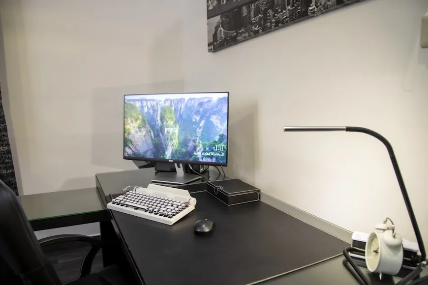 A compact home office corner with a desk, chair, and warm natural light in a small room.