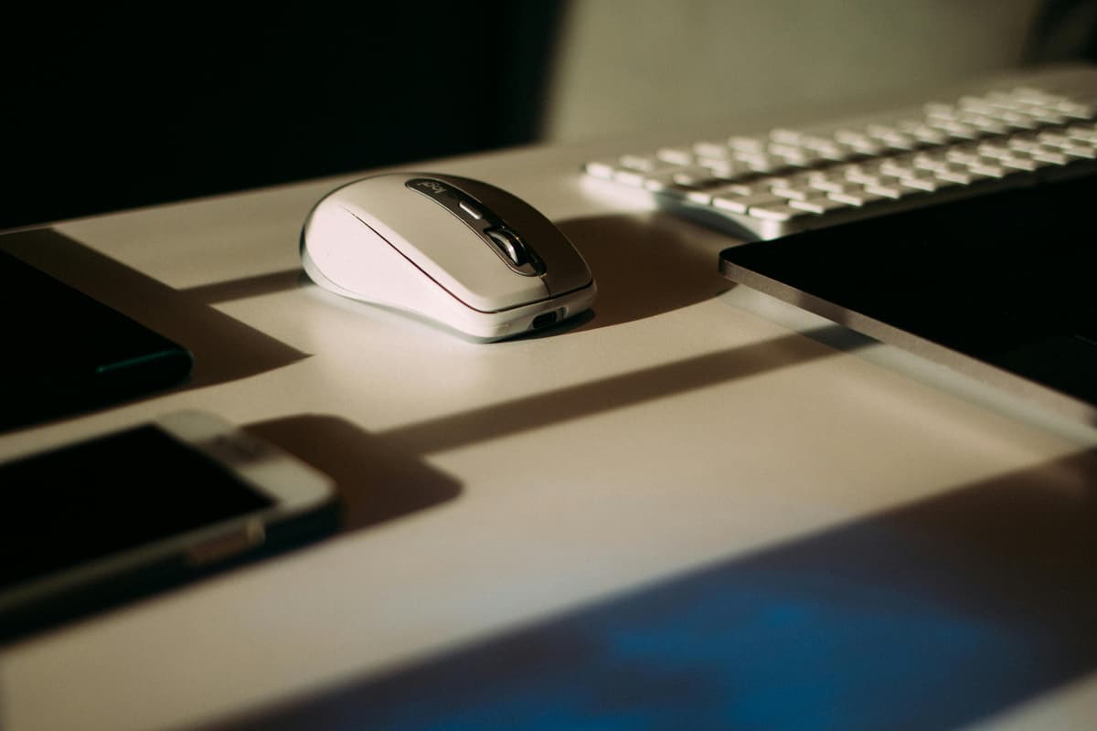 A close-up desk setup with a wireless mouse beside a keyboard on a clean work surface.