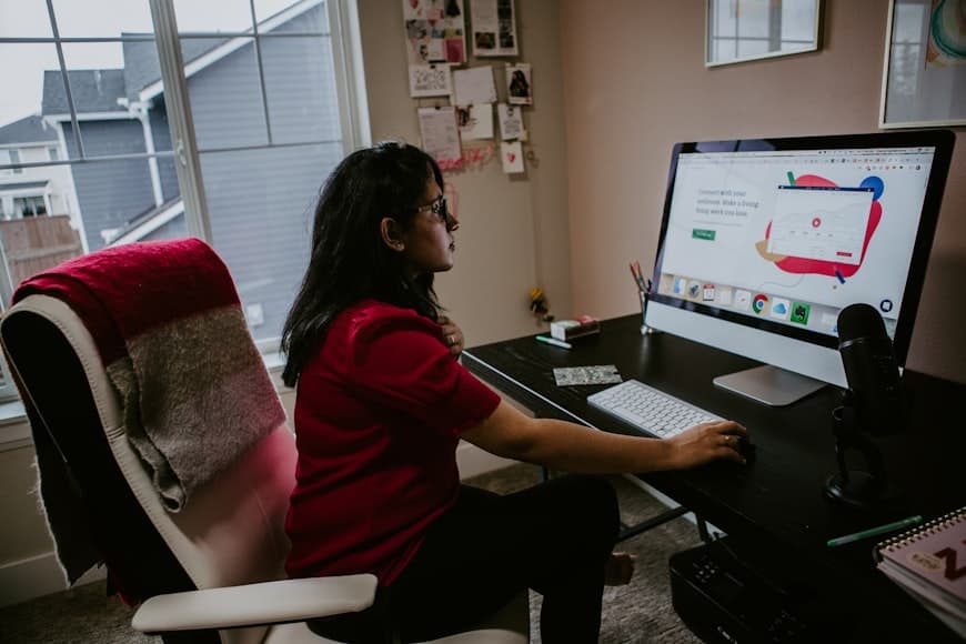A desk setup with a monitor, laptop, and seated work position in a bright room.