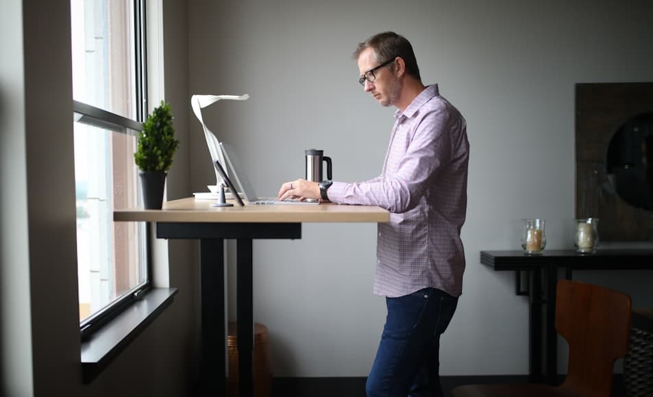 A minimalist standing desk setup with a monitor and accessories in a bright workspace.