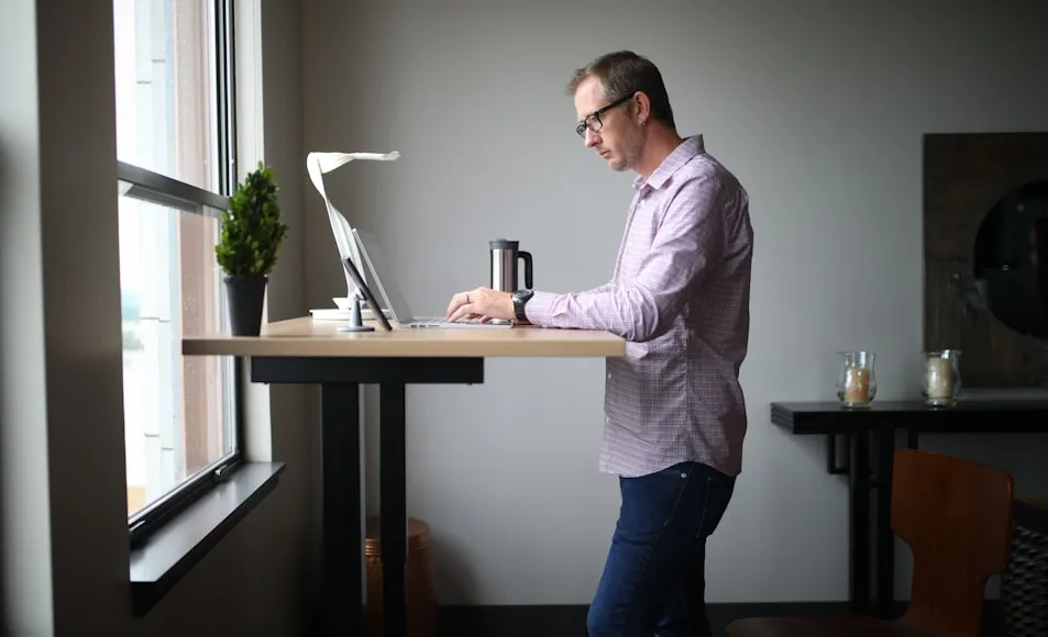A minimalist standing desk setup with a monitor and accessories in a bright workspace.