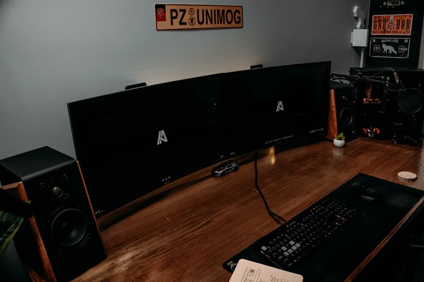 A clean desk setup with a monitor, keyboard, and warm ambient light in a small workspace.