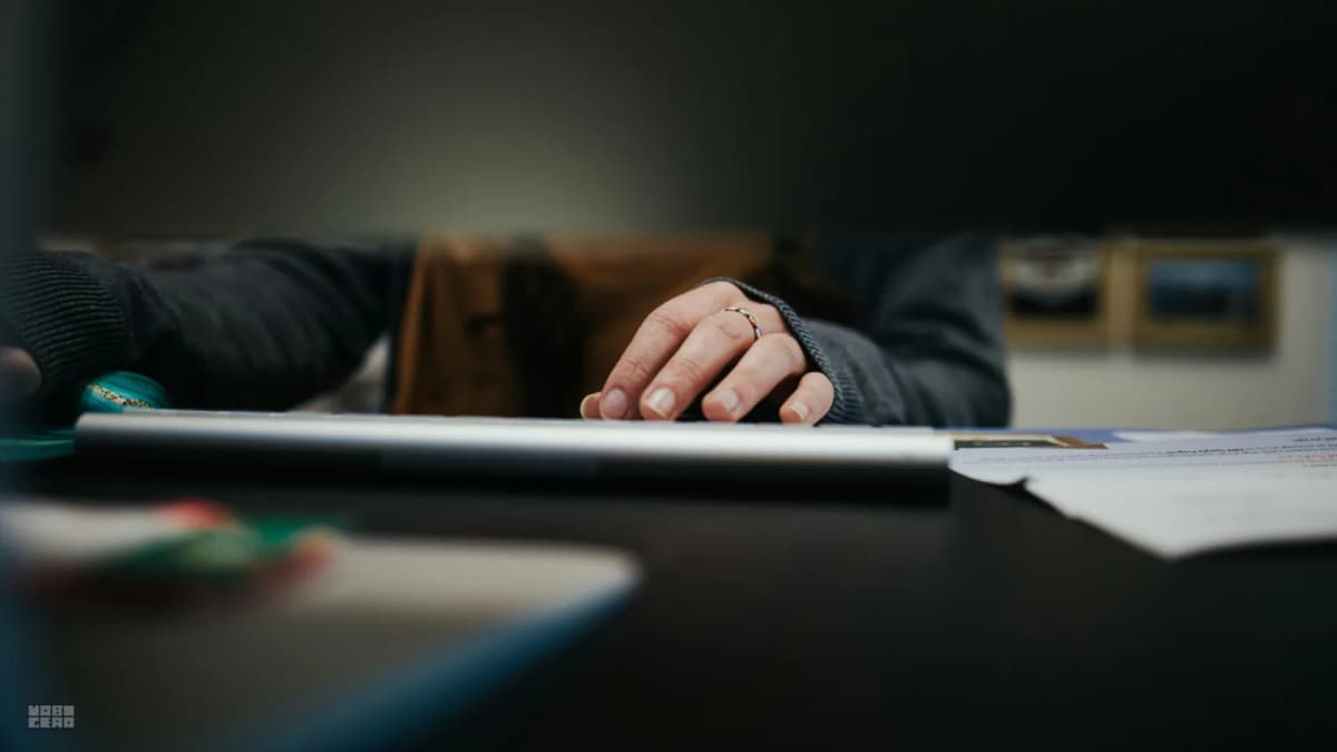 A person seated at a desk with forearms resting on the surface, demonstrating correct elbow-to-desk height alignment.