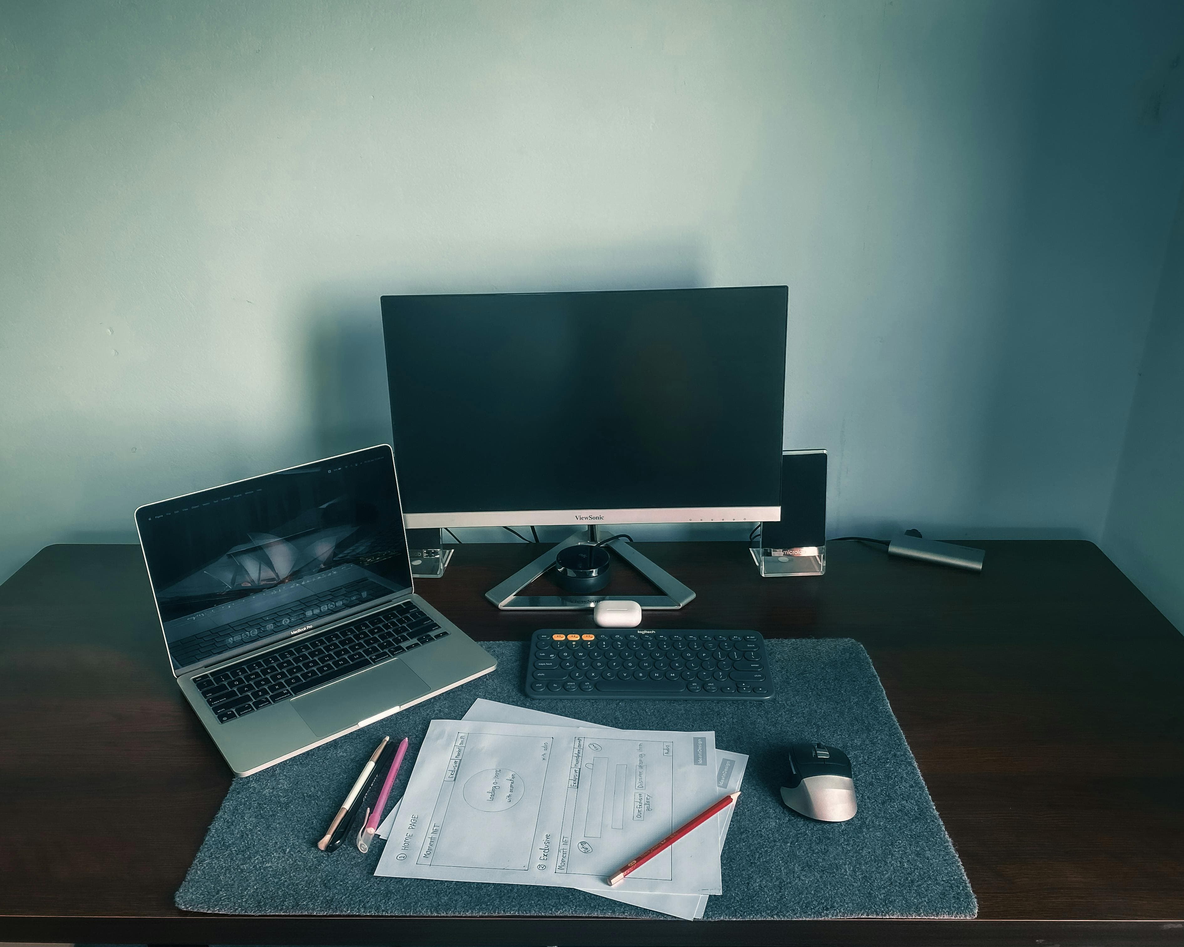 A person working at a desk with a laptop, notebook, and other workspace items in view.