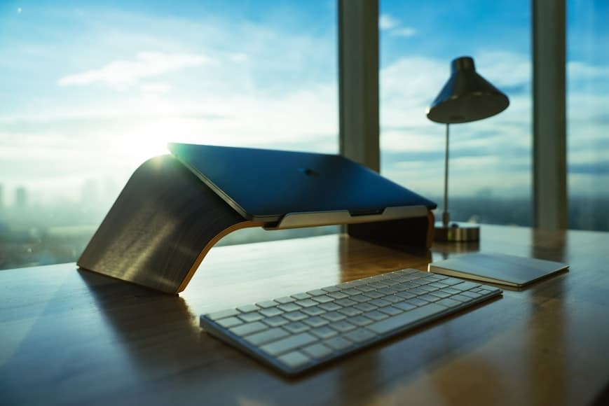 A closed laptop standing vertically on a desk in a minimalist workspace.