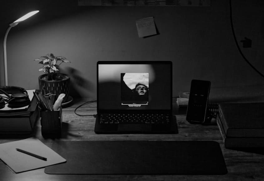 A calm desk setup with a monitor, keyboard, and warm workspace lighting in a tidy room.
