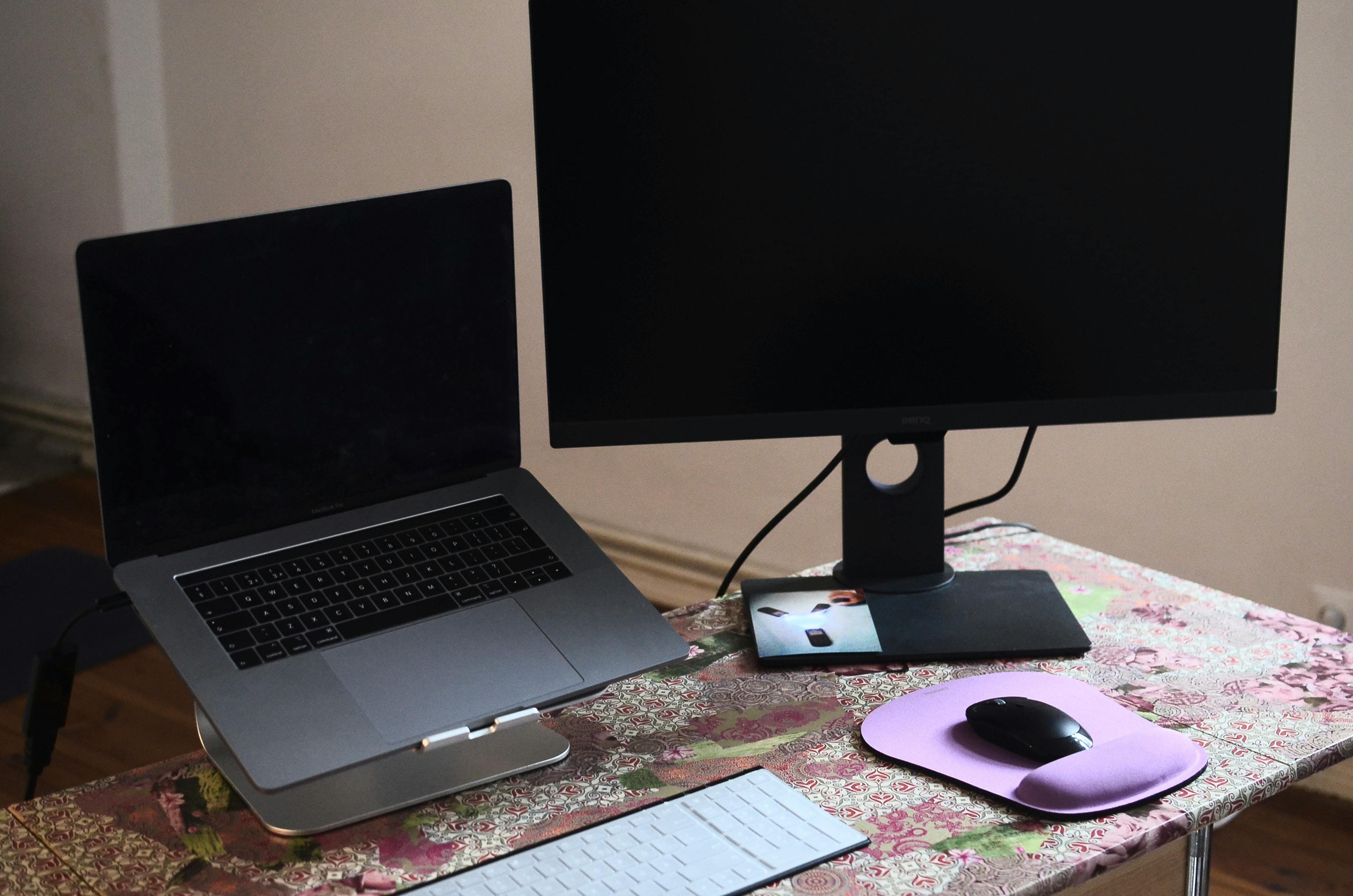 A modern desk setup with an external monitor, laptop, keyboard, and chair in a workspace.