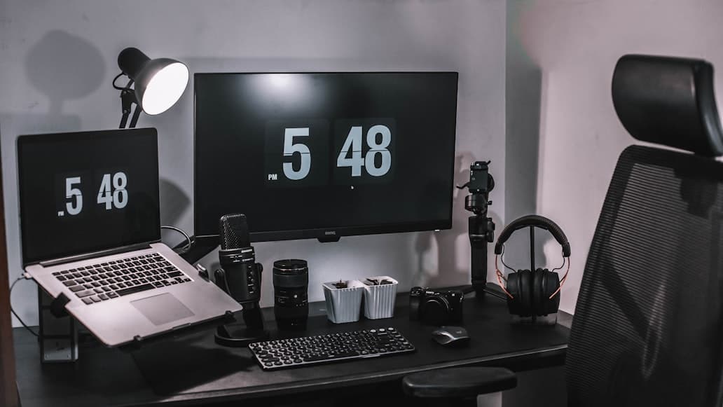A tidy desk setup with a monitor, laptop, and soft natural light in a calm room.