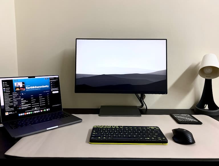 A compact desk setup with a monitor and accessories in a moody home office scene.