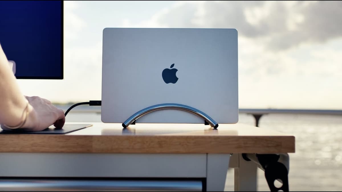 A MacBook docked vertically in the Twelve South BookArc Flex stand beside a large external display.