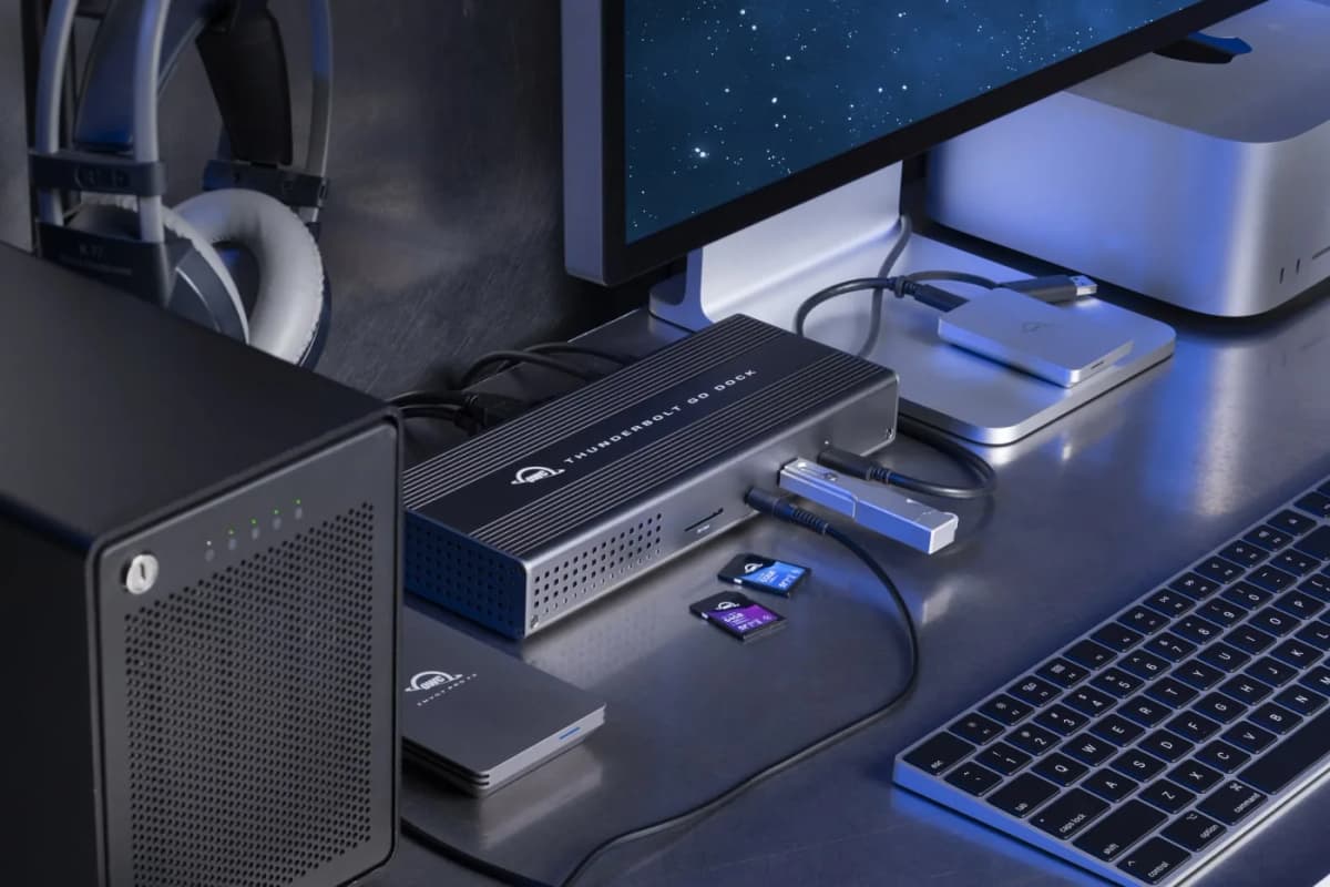 A compact laptop dock sitting beside a monitor in a clean desk setup with cables routed neatly away.