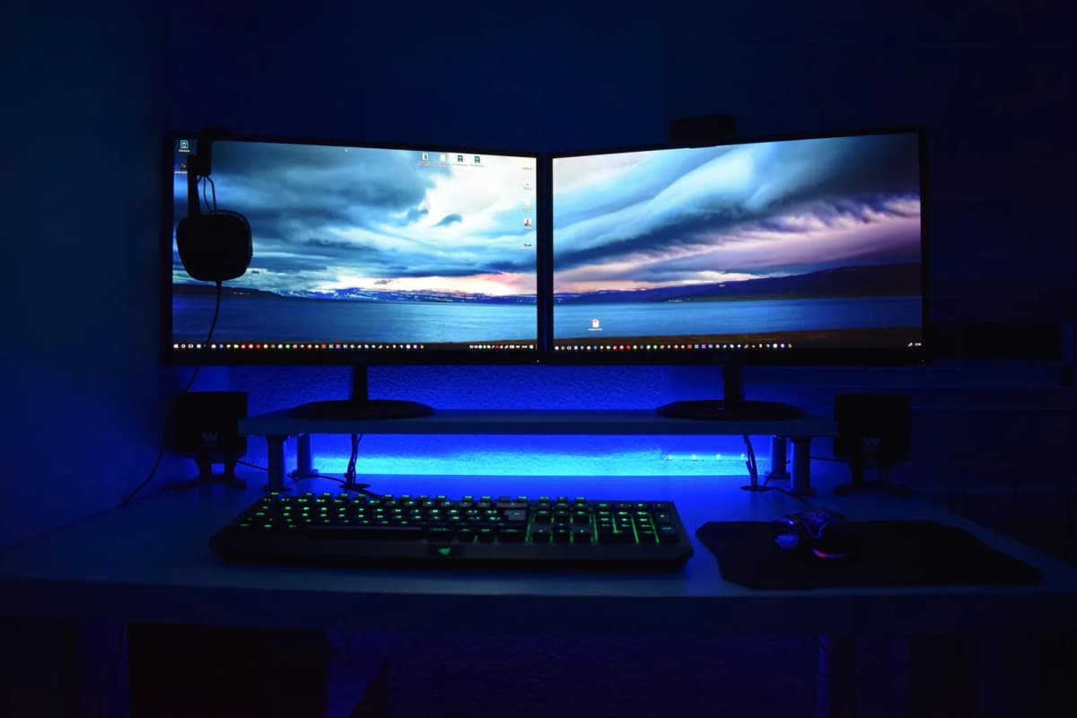 A dual-monitor desk setup with two displays on a raised shelf above a keyboard and mouse.