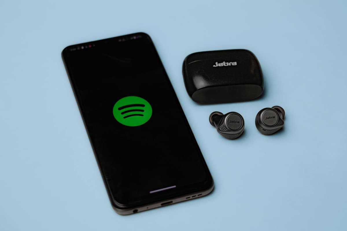 An assortment of audio gear — headphones, a soundbar, and a small wireless speaker — arranged on a minimal desk.